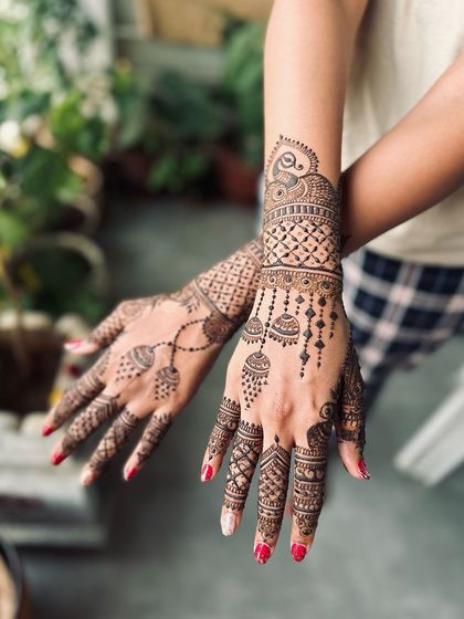 A beautiful example of a modern party mehndi design, with hanging jhumka (earring) motifs and delicate chains that create a jewelry-like effect on the skin.