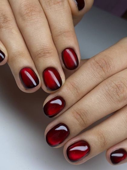 A deep red cat-eye manicure on short, natural nails. The magnetic effect adds a touch of mystery and sophistication to this classic color.