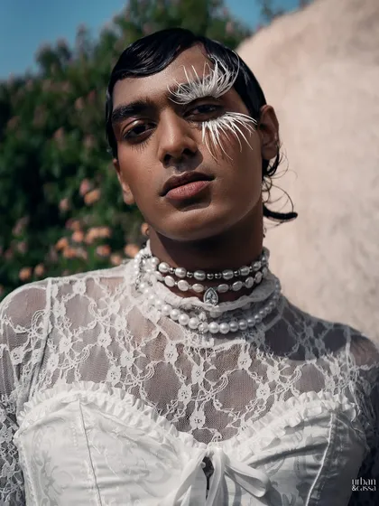 A detailed close-up of the feather eye makeup, pearl choker, and wet-look hair, showcasing the intricate details of the styling.
