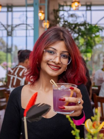 A guest with a vibrant purple cocktail, her smile as bright as her drink.