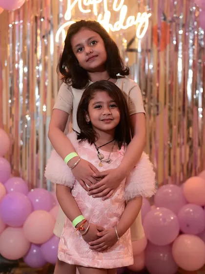 Sisters sharing a sweet hug at a birthday party. It's wonderful to see siblings and friends bonding during the celebration.