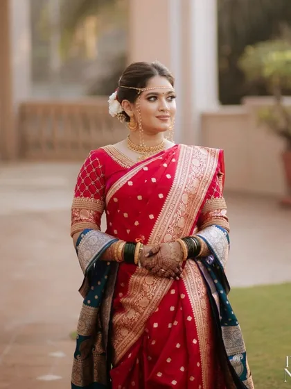 A full-length shot of the bride in her stunning red and blue Paithani saree. The entire look is a perfect blend of tradition and elegance.