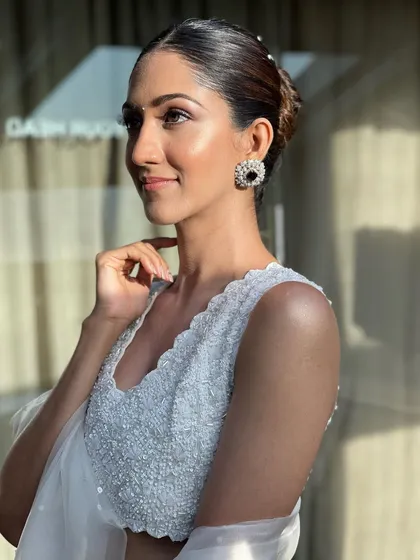 A sun-kissed shot highlighting the clean lines of the sleek bun and the client's glowing makeup.