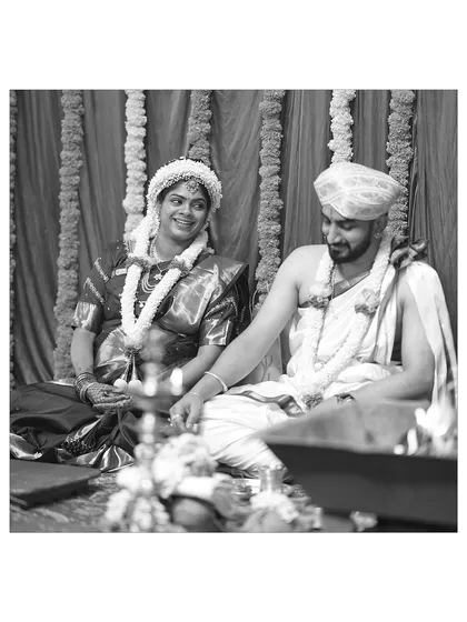 A candid black and white shot of a couple during their baby shower ceremony. The image captures a quiet, shared moment between the soon to be parents.