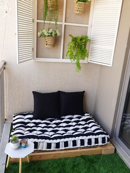 A full view of the cosy reading nook, showing how the pallet bench, mattress, and decorative window come together. The small side table and plant complete this perfect spot for relaxing with a book.