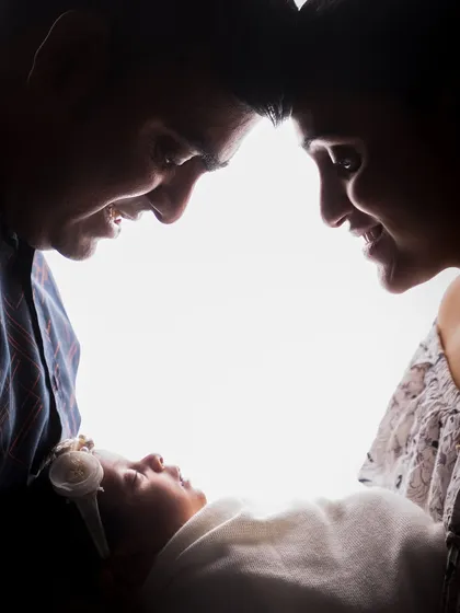 A close-up version of the family silhouette portrait. This tight crop intensifies the feeling of intimacy and the private world shared between new parents and their child.