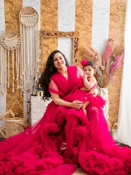 A mother and daughter, both in beautiful red dresses, share a sweet moment in our boho-themed studio setup.
