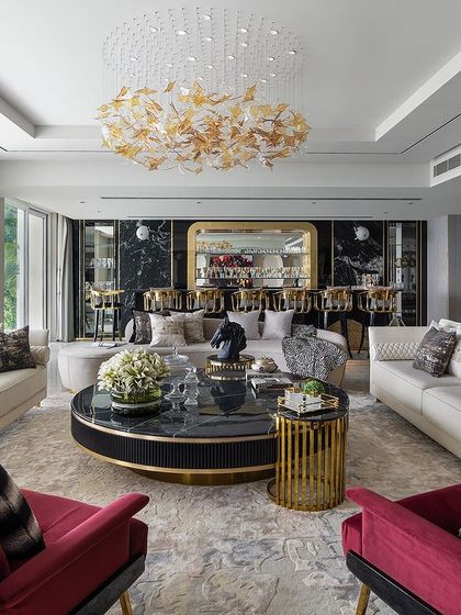 A luxurious living room where we provided custom furniture. The space features white sofas, bold red armchairs, and a statement black and gold coffee table, all unified by a stunning leaf-motif chandelier. This demonstrates how our bespoke furniture can transform a space.