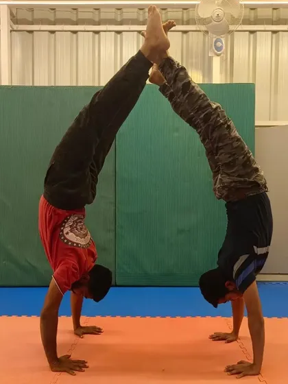 A symmetrical partner handstand pose. This exercise is excellent for building shoulder strength and learning to mirror your partner's movements for perfect synchronization.