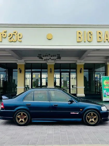 A classic modified blue Honda City parked perfectly in front of our main entrance, showcasing the pride car owners take in their vehicles at our spot.