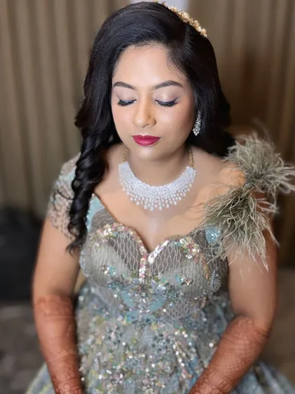The complete look is pure glamour, from the feathered gown to the diamond necklace and the bold makeup.
