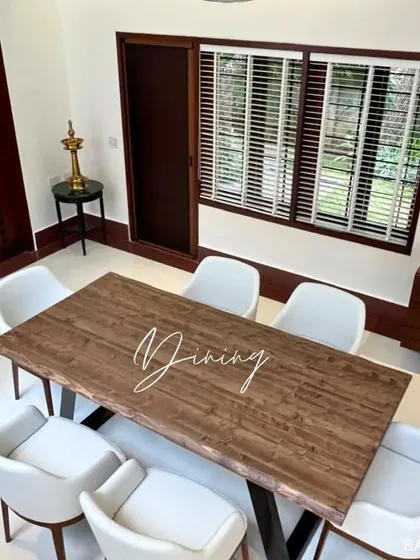 A dining area that blends rustic and modern styles, with a live-edge wood table, contemporary white chairs, and dark wood window frames.