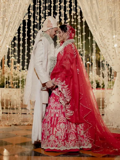 A tender moment between the newly married couple, framed by a curtain of delicate white flowers. The soft lighting and intimate pose create a timeless portrait of love and commitment.