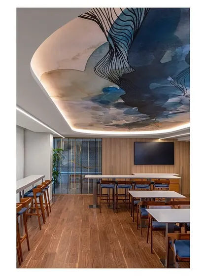 The dining area in 'The Office with A View', featuring a custom capsule-shaped ceiling graphic. We repurposed furniture from the client's previous office and added new elements like this ceiling detail to refresh the space.
