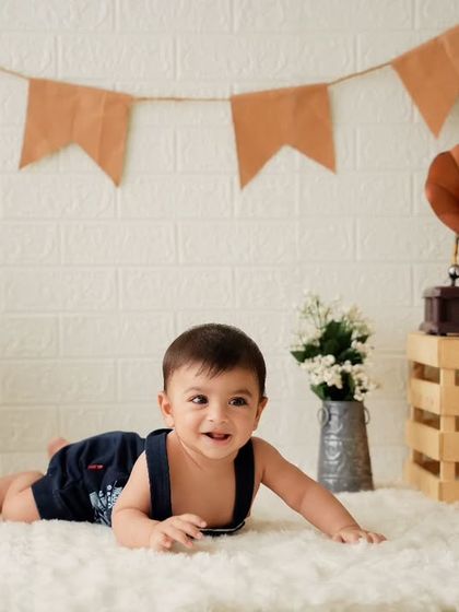A happy baby boy during his milestone photoshoot. I use props like teddy bears and vintage items to create a charming and timeless look.