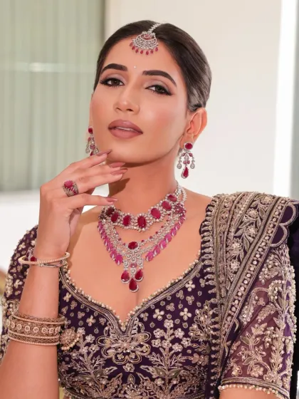 A detailed portrait focusing on the bride's makeup and the stunning ruby and diamond necklace, which adds a layer of opulence to the look.