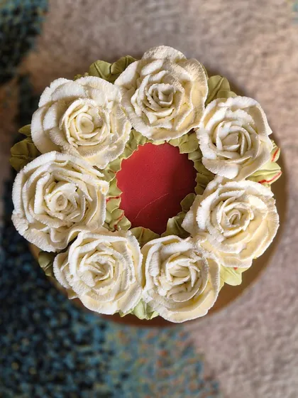 A top-down view of the red cake, showing the beautiful wreath of white buttercream roses.