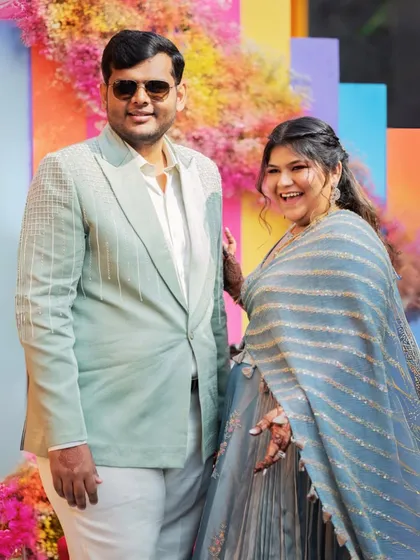 A happy, candid portrait of the couple at their vibrant carnival-themed event. Their smiles say it all.
