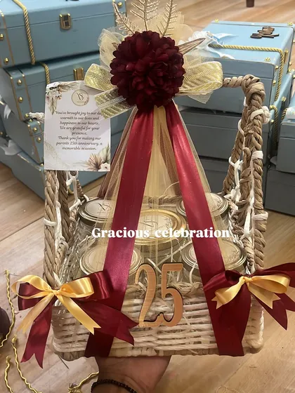Celebrating a 25th anniversary is a grand affair, and the return gifts should be just as special. This luxurious basket hamper, decorated in rich maroon and gold, is filled with five different jars of delicious eatables and marked with a '25' to honor the silver jubilee.