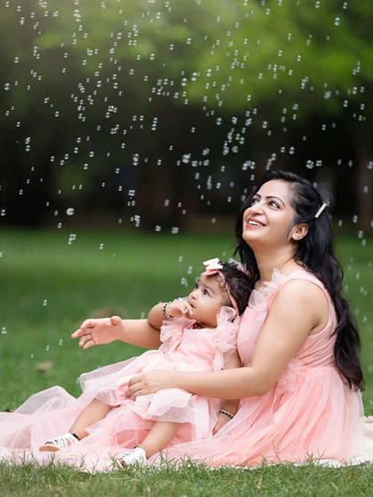 A mother and daughter enjoy a shower of bubbles during their outdoor session. Using simple props like bubbles is a great way to get genuine smiles from children.