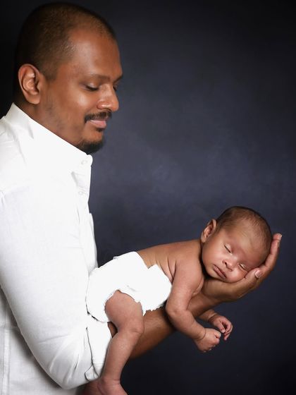 A proud father holds his tiny newborn in the palm of his hand. This classic pose is a wonderful way to show just how small and precious a baby is in those first few weeks.