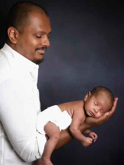A proud father holds his tiny newborn in the palm of his hand. This classic pose is a wonderful way to show just how small and precious a baby is in those first few weeks.