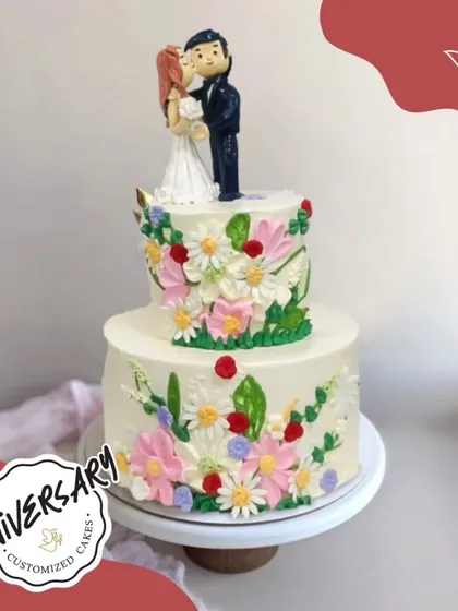 This two-tier anniversary cake combines two of our favorite things: beautiful, hand-piped flowers and a personalized couple topper. It's a perfect blend of elegance and personal storytelling for a celebration in Dwarka.