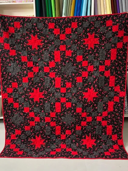 A striking star quilt in red and black, with a floral print fabric.