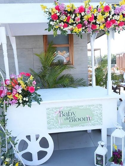 A 'Baby in Bloom' cart decorated with bright, fresh flowers and whimsical props, serving as a beautiful and functional piece of decor.