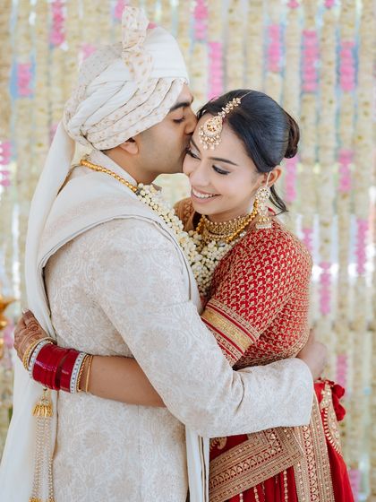 A tender moment as the groom kisses his bride on the forehead, their smiles radiating happiness.