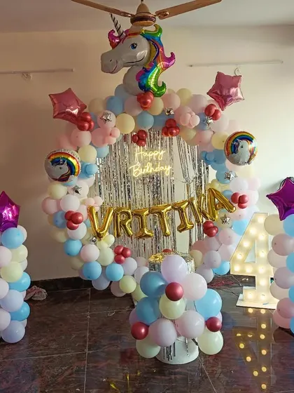 A unicorn-themed 4th birthday party with a full room setup. It includes a balloon arch with a unicorn head, a neon sign, a light-up number, and balloon pillars.