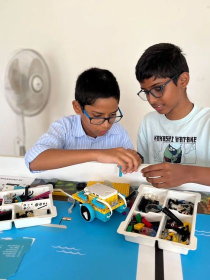 Two students make fine-tuned adjustments to their robot, preparing for the Indian Robotics Olympiad. This attention to detail is what separates good robots from competition-winning ones.