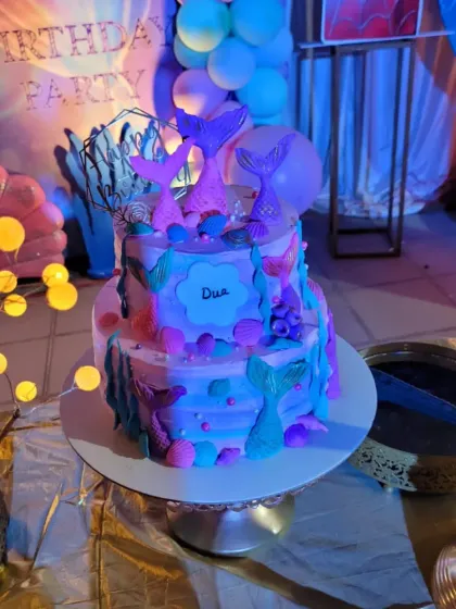 A stunning two-tier mermaid-themed cake that perfectly matches the party's decor.