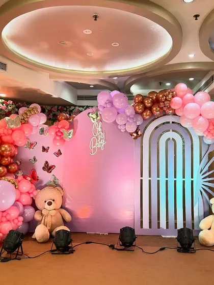 A grand 'Oh Baby' shower with a butterfly theme. This stage features a large pastel purple backdrop, butterfly wing-shaped balloon arrangements, and cute teddy bears for a whimsical touch.