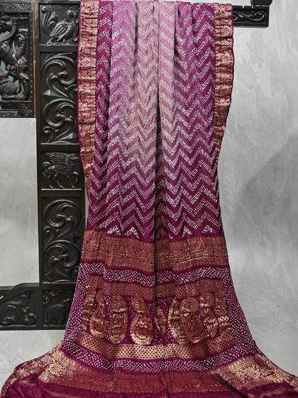 A vibrant magenta Bandhani saree with a chevron pattern. Bandhani, or tie-dye, is another beautiful resist-dyeing technique that creates stunning patterns.