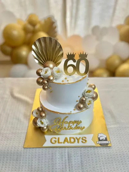 A stunning two-tier cake for a 60th birthday. The white and gold theme with floral accents and a fan topper creates a look of pure elegance.