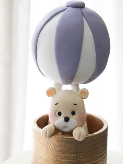 A close-up of the adorable teddy bear in his hot air balloon, a popular and dreamy theme for baby shower cakes.