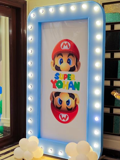 A personalized "Super Yohan" welcome sign with a Mario theme, framed in a blue marquee-lit border. This custom sign makes the birthday boy the hero of his own game.