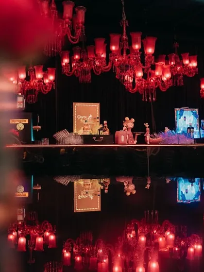 Red chandeliers cast a dramatic glow over the glossy black dance floor, reflecting the light for a stunning effect.