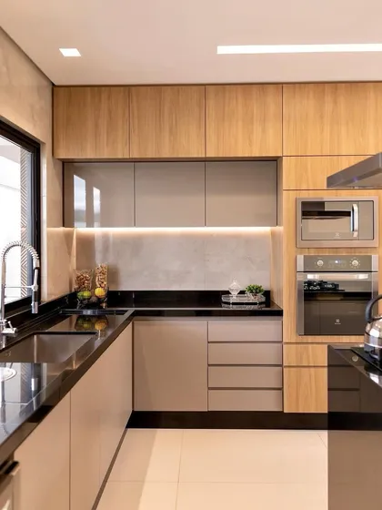A look at a compact and efficient modular kitchen I designed and executed. It features a dual-tone finish with wood-grain upper cabinets, built-in appliance slots for a microwave and oven, and under-cabinet lighting for a functional workspace.