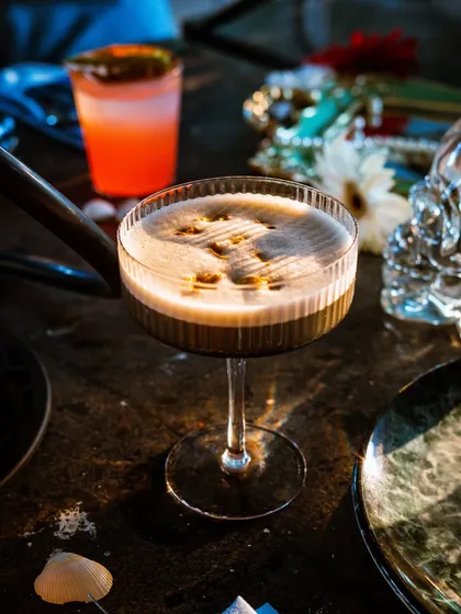 An espresso martini with smoke being infused at the table. This shot captures the drama and sensory experience of a high-end cocktail.