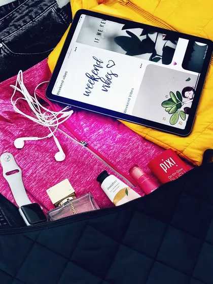 A closer look at the 'what's in my bag' flatlay, focusing on the tech and beauty products like my Apple Watch, perfume, and Pixi lip balm.