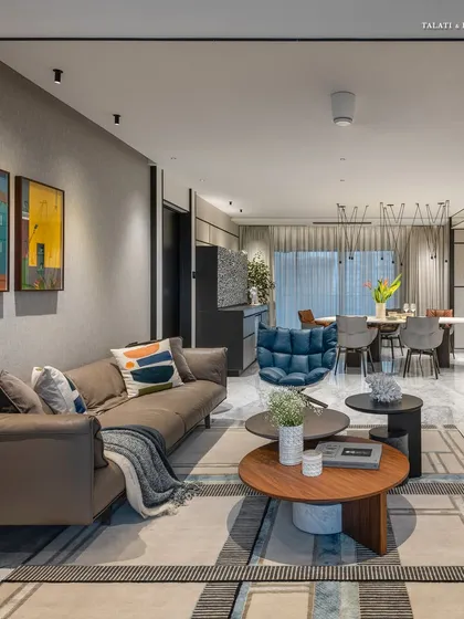 A wider view of a collector's home, where the living and dining areas merge into a cohesive, art-filled space. The design proves that simplicity speaks loudest when every detail, from the tufted blue lounge chair to the curated art, is handpicked with intention.