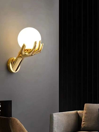 A unique, sculptural wall light featuring a hand holding a glowing orb. This is a true conversation starter for any room.
