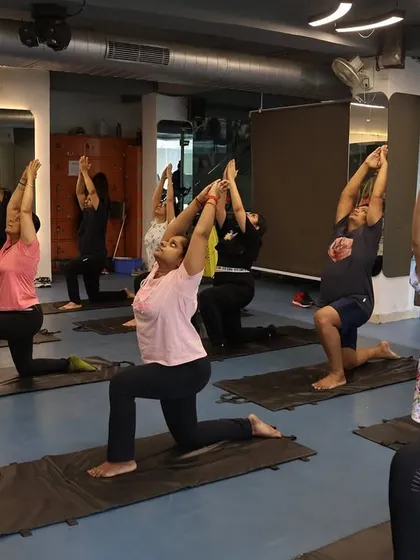 Members in the Low Lunge pose (Anjaneyasana), a great stretch for the hips and thighs, practiced together as a group.