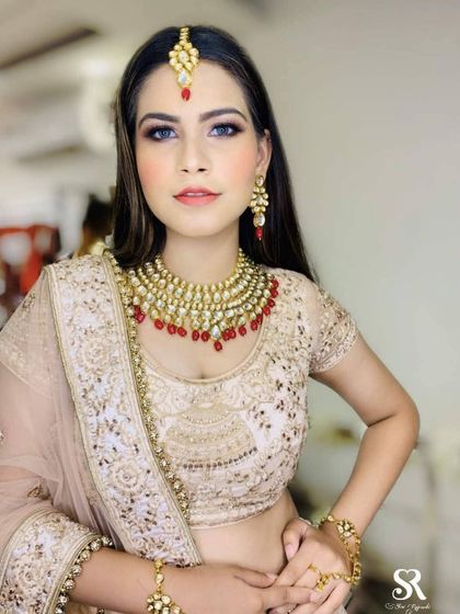 This client rented a beautiful beige and gold lehenga with red-beaded Kundan jewellery. It's a versatile and elegant choice suitable for a variety of wedding functions.