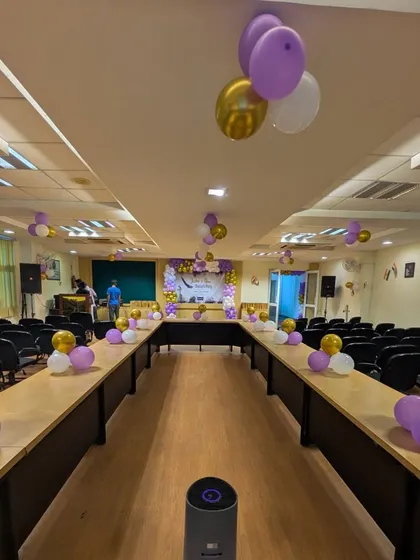 This is a view of a decorated conference hall, showing how I can add a festive touch to a professional setting. Simple balloon clusters on the tables and a larger arrangement on stage make the space feel celebratory but not cluttered.