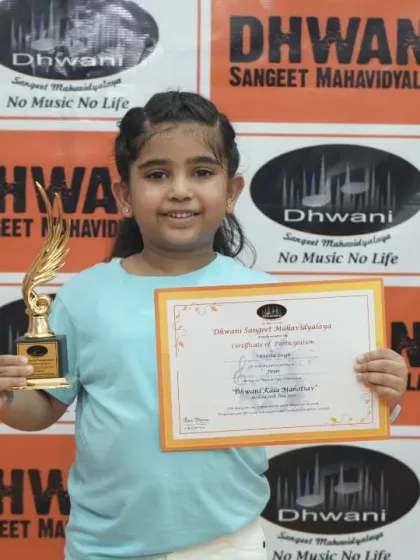 A young student smiles brightly, holding her certificate and trophy.