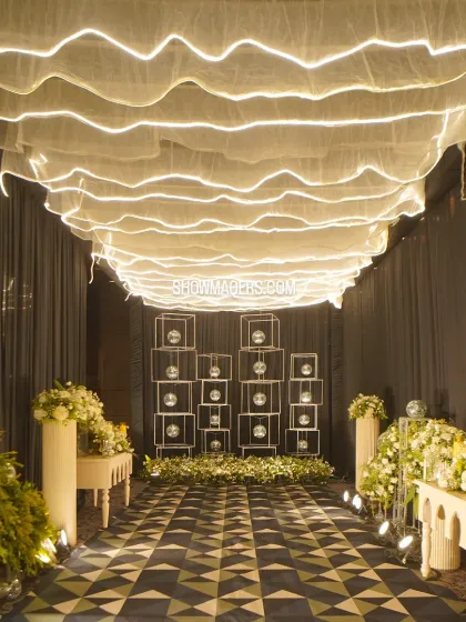 A dramatic entrance walkway with a geometric-patterned floor, flanked by floral arrangements and leading to a modern art installation.