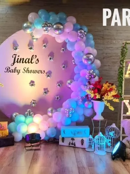 Jinal's baby shower with a circular backdrop, a cascade of blue and pink balloons, and light-up "BABY" letters.